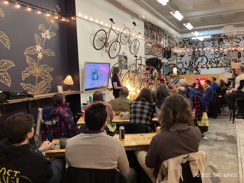 A group of people sitting in a cafe listening to a speaker at BIKE MINDS.