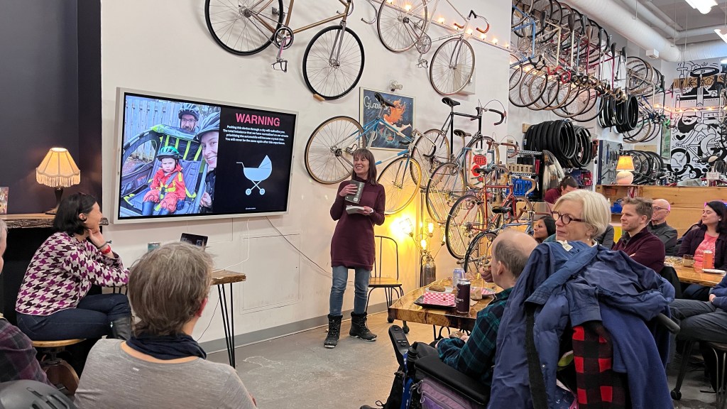 A group of people sitting in a cafe listening to a speaker at BIKE MINDS.